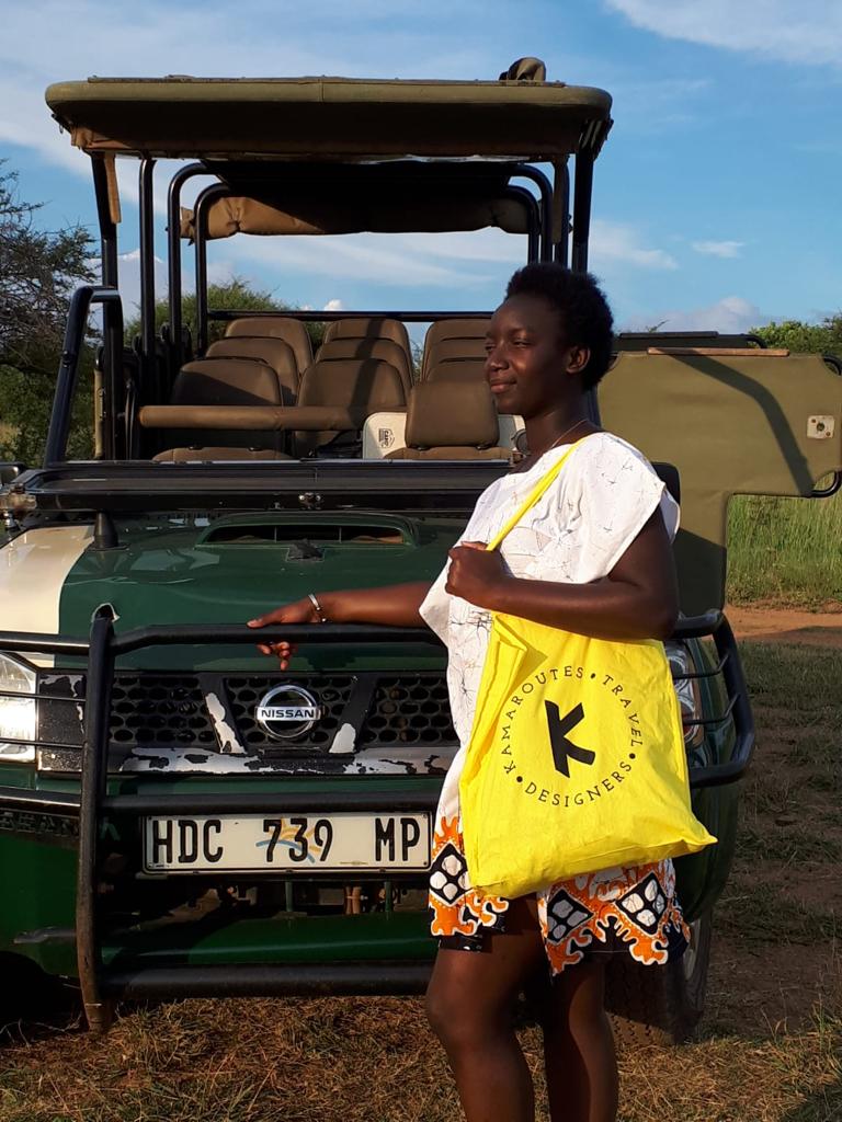 Woman standing in open field next to Safari car